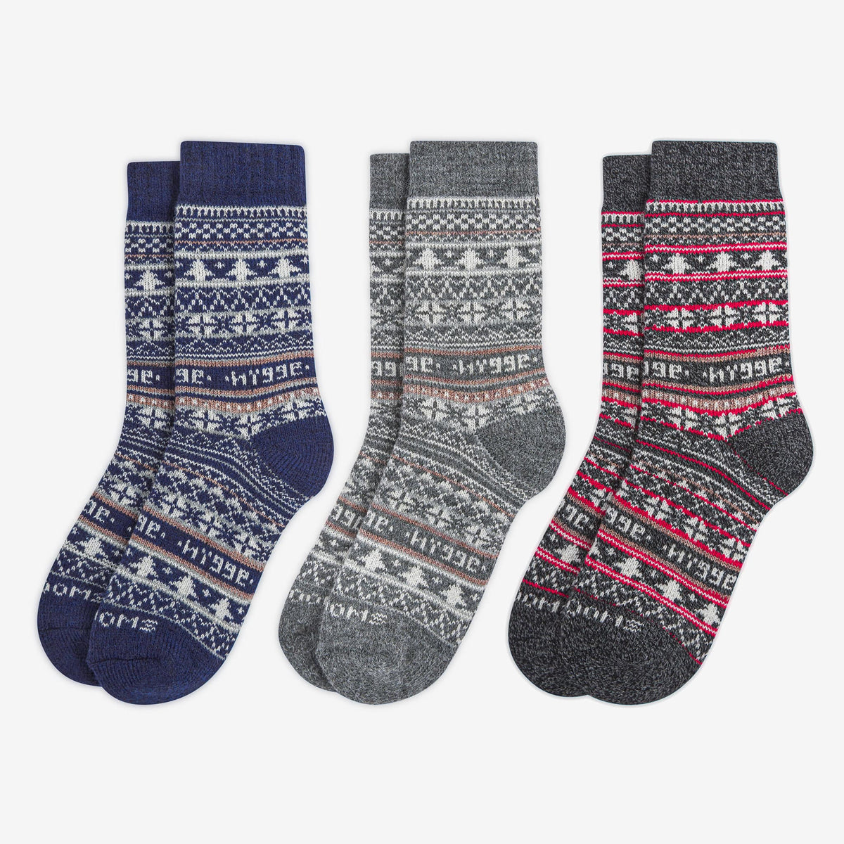 Three patterned merino wool Swoollies socks with the text 'hygge' knitted on it. The socks are thick. Socks are on a light grey background