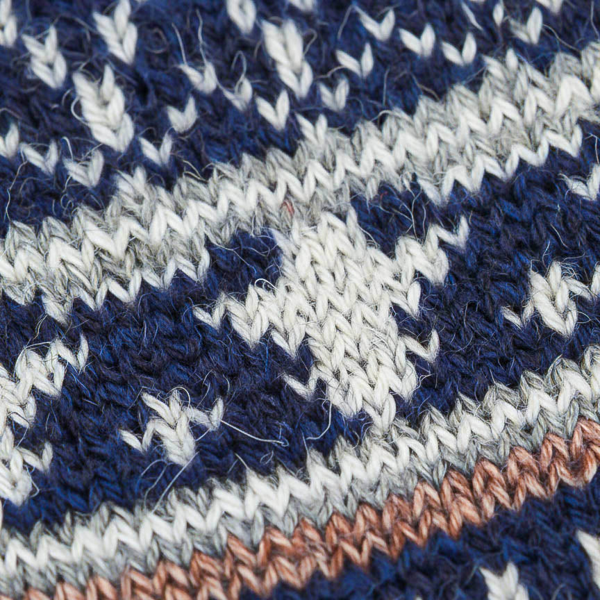 Close-up of a knitted fabric with blue, white, and orange pattern