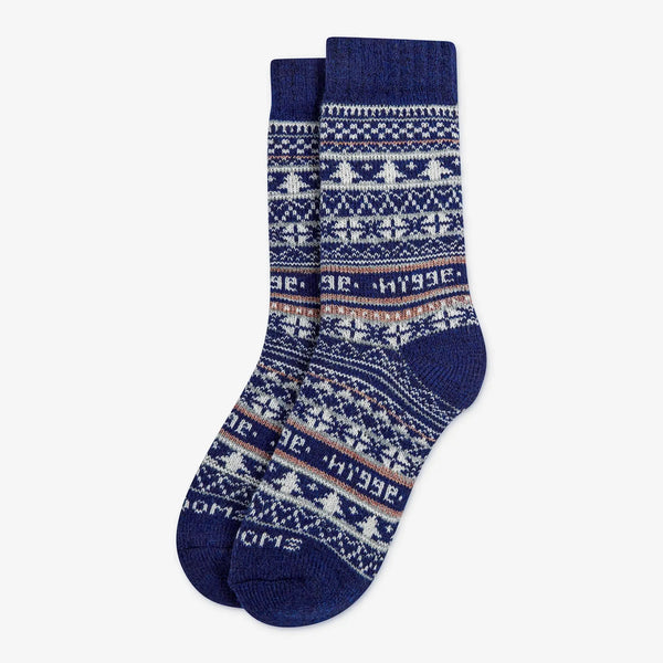 Navy blue patterned merino wool Swoollies socks with the text 'hygge' knitted on it. The socks are thick. Socks are on a light grey background